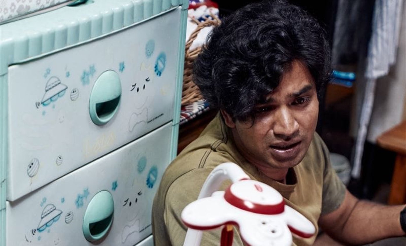 Anupam Tripathi as Abdul Ali in 'Squid Game' k-drama sitting against a baby dresser