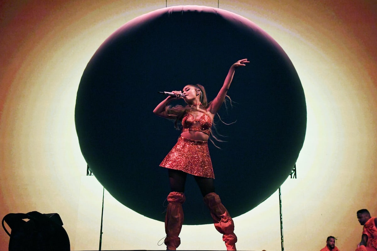 Ariana Grande singing in front of a large circle backdrop