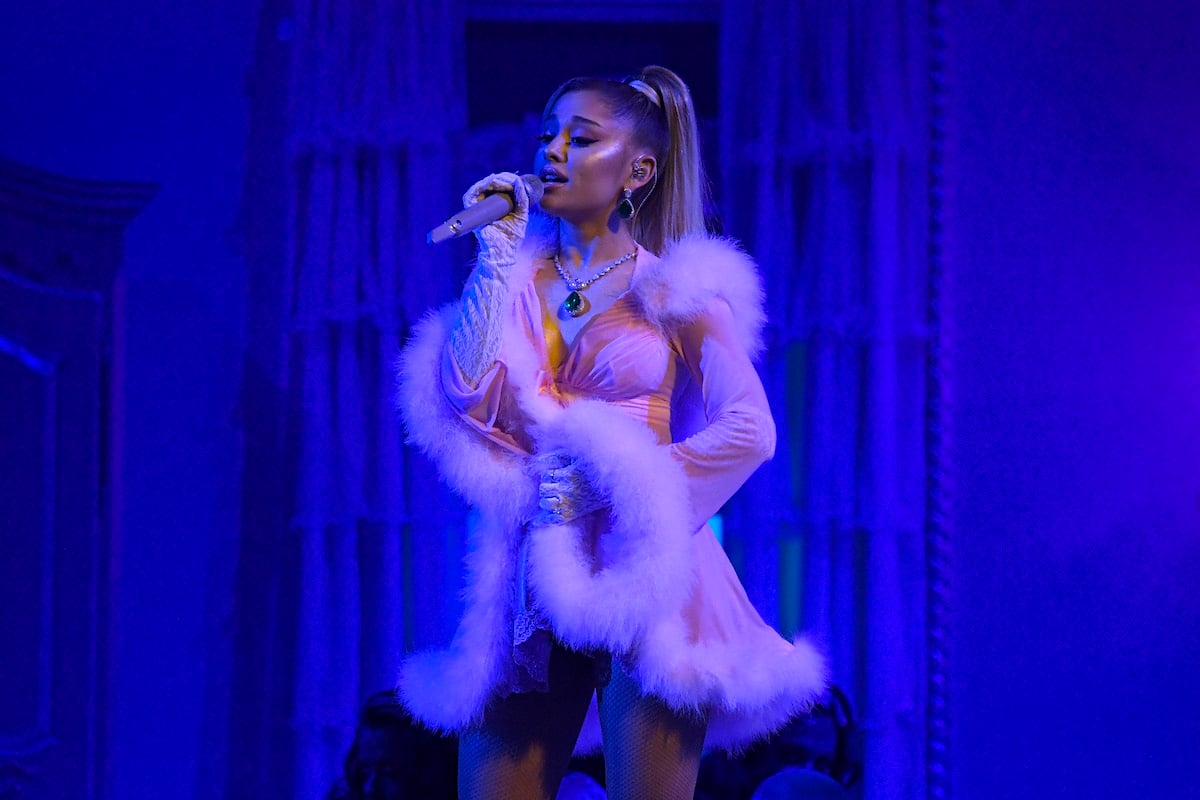 Ariana Grande performs on stage in a feathered costume.