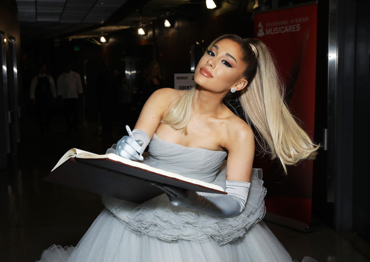 Ariana Grande signs a book at an event.