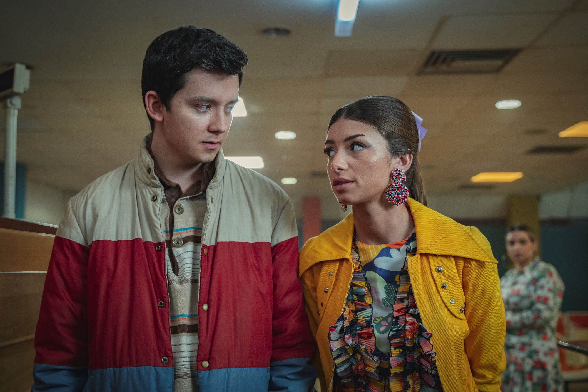 Asa Butterfield as Otis Milburn, Mimi Keene as Ruby Matthews of 'Sex Education' walking together.