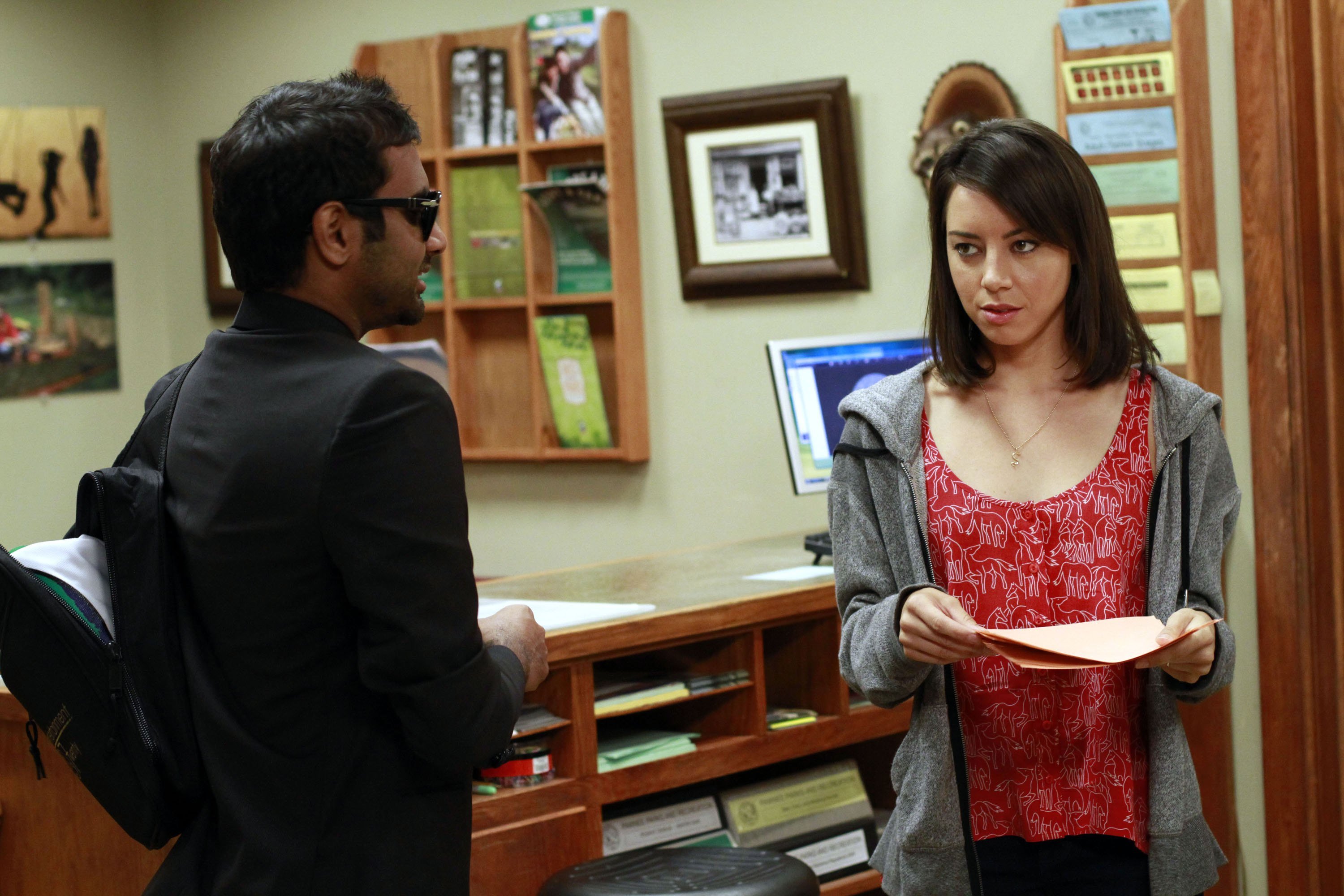 Aubrey Plaza and Aziz Ansari stand in the office in Parks and Recreation