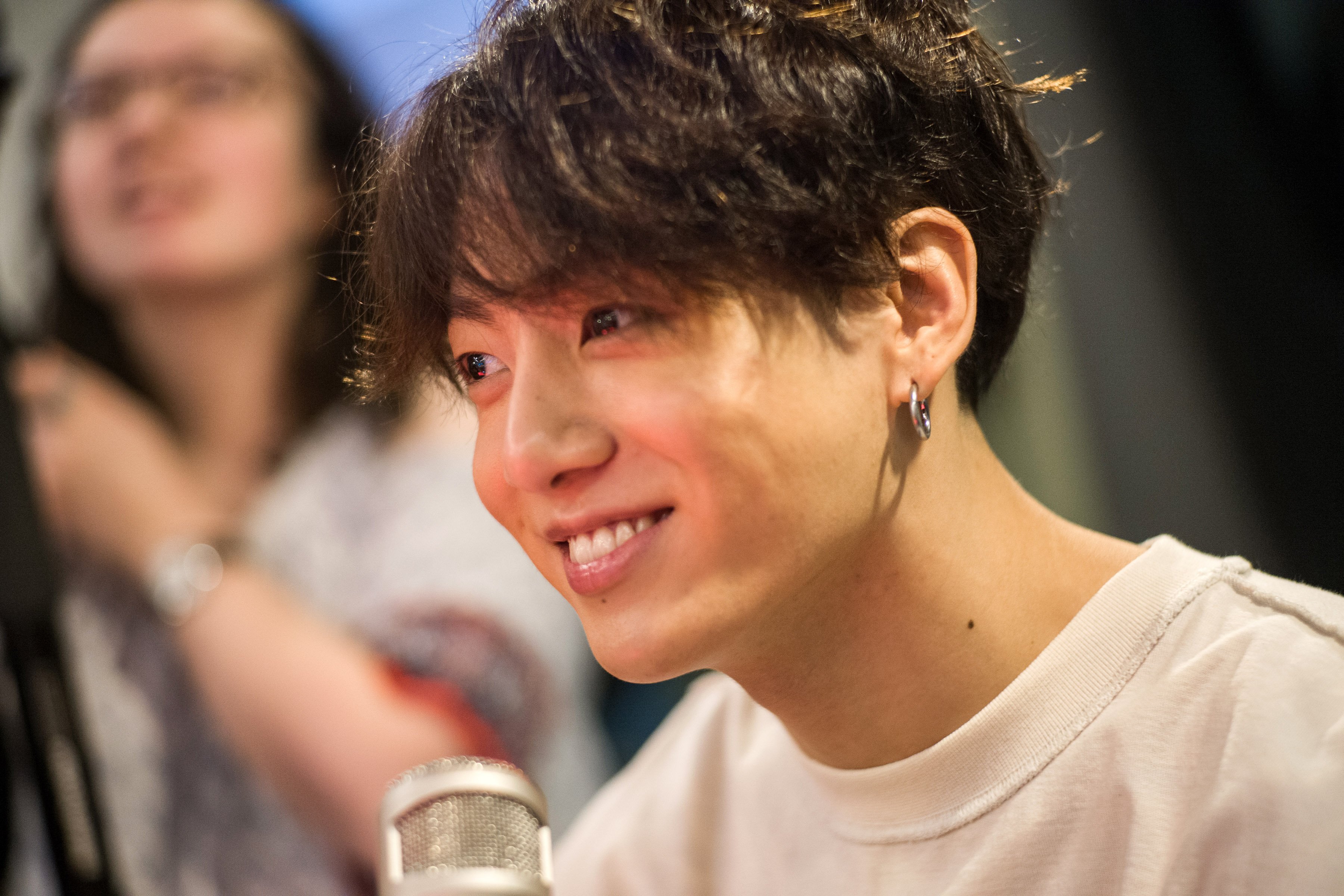 Jungkook of BTS smiles while wearing a white shirt