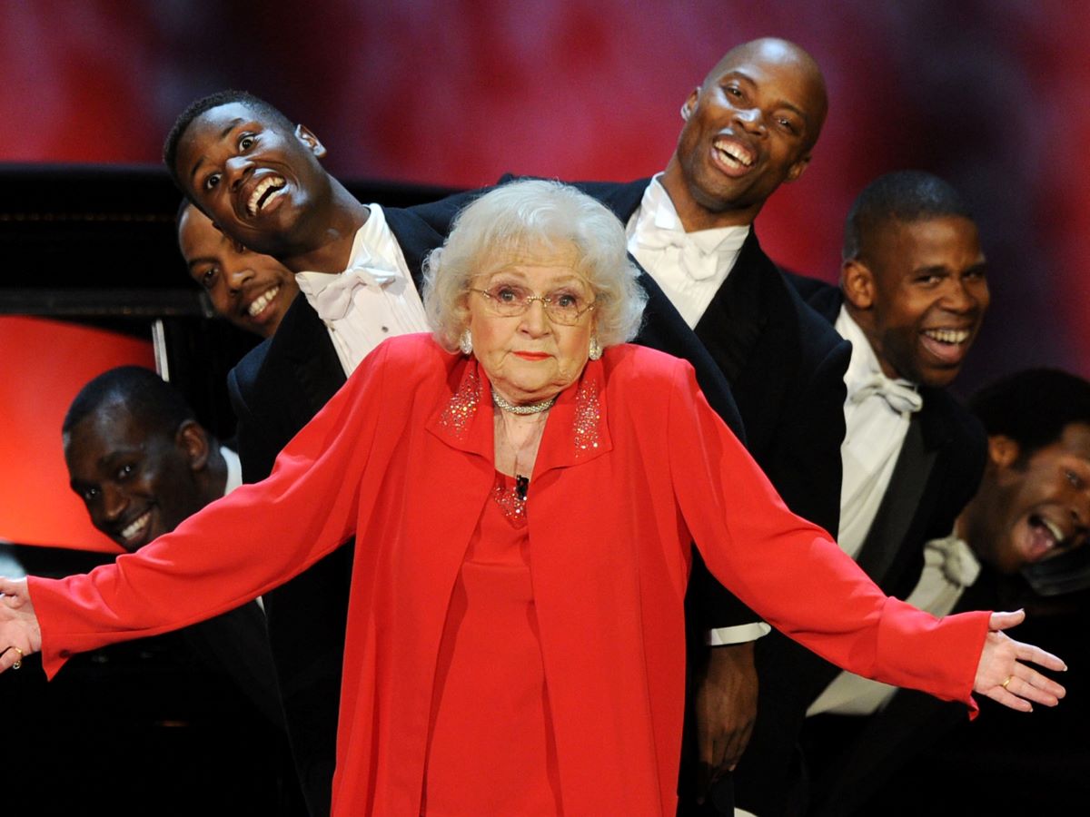 Betty White in red and glasses, shrugging
