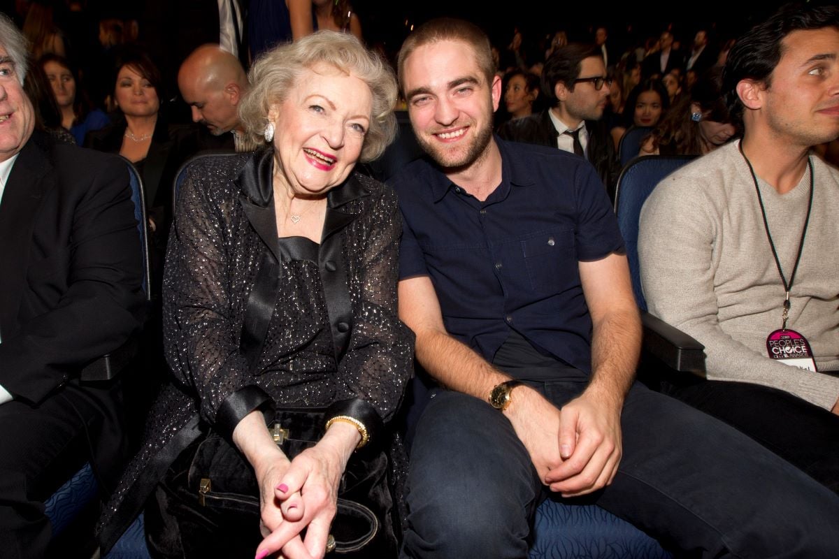 Betty White and Robert Pattinson sitting side-by-side, both in black and smiling