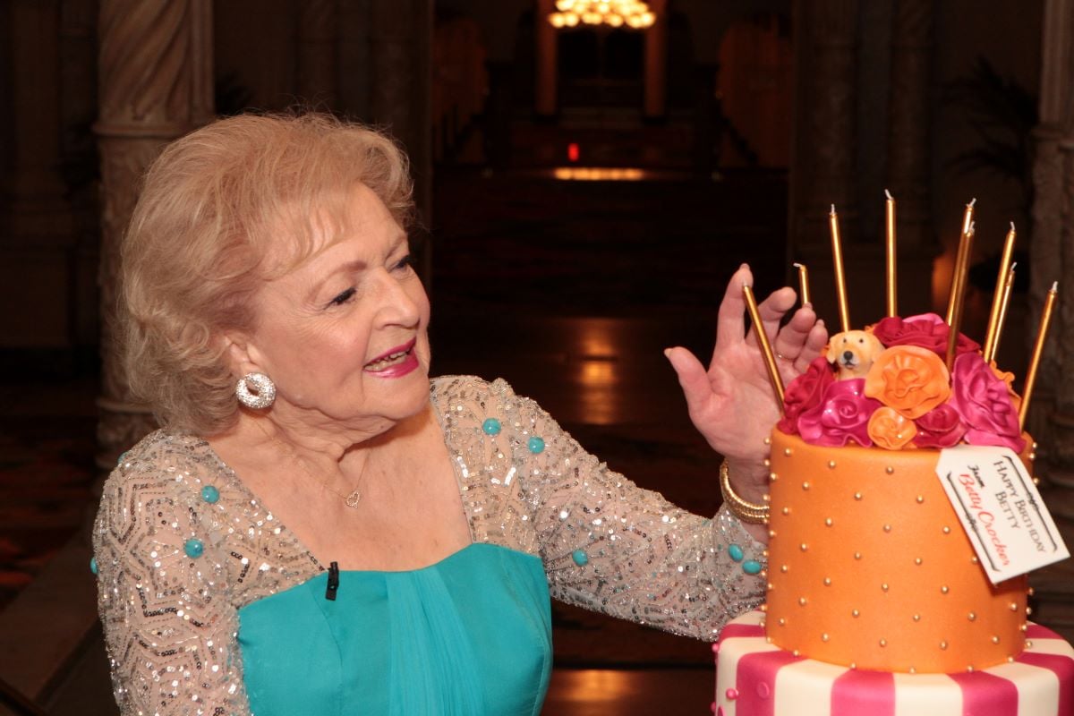 Betty White in a blue dress with a colorful cake