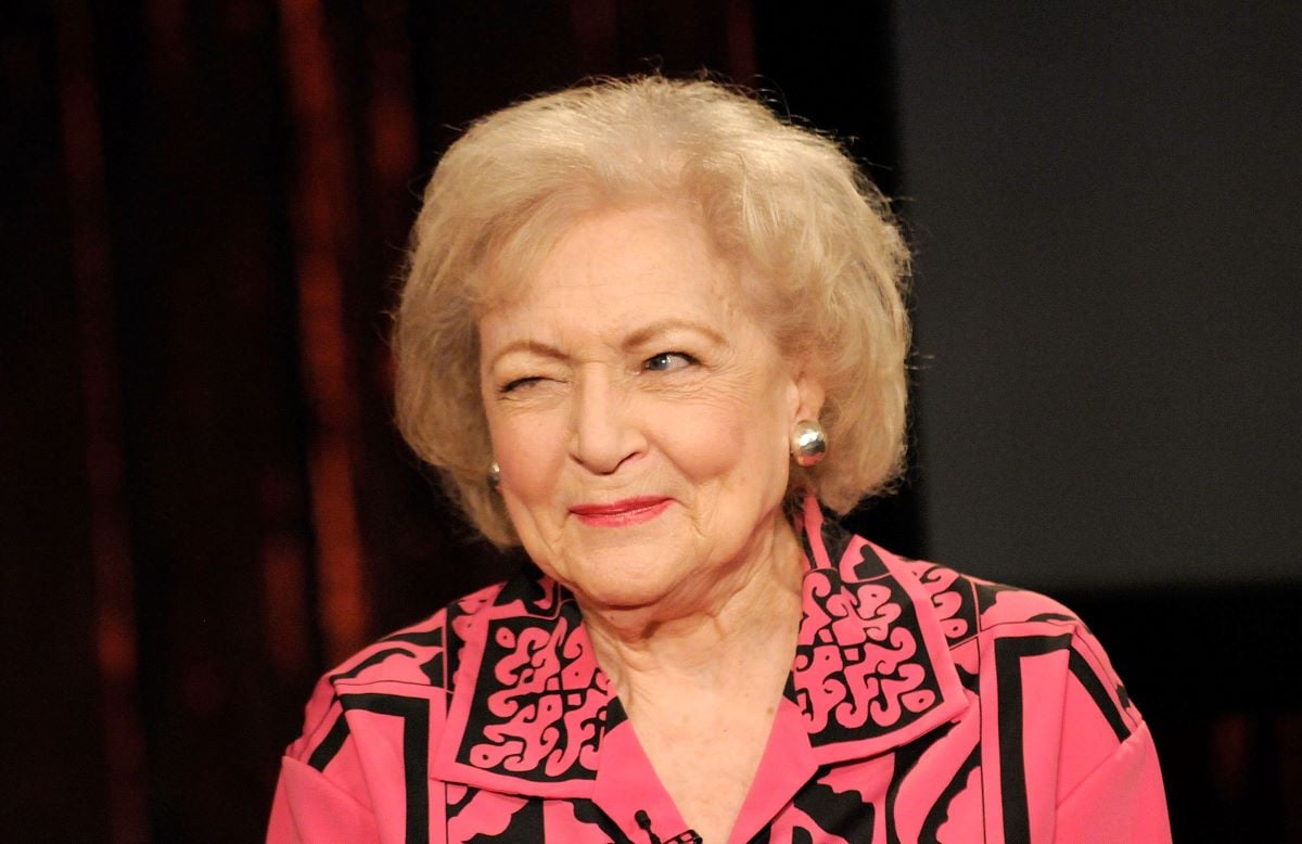 Betty White in a pink shirt winking