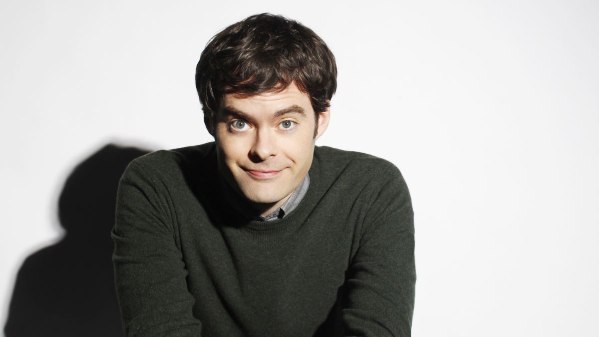 Bill Hader poses in front of a white background, smiling slightly