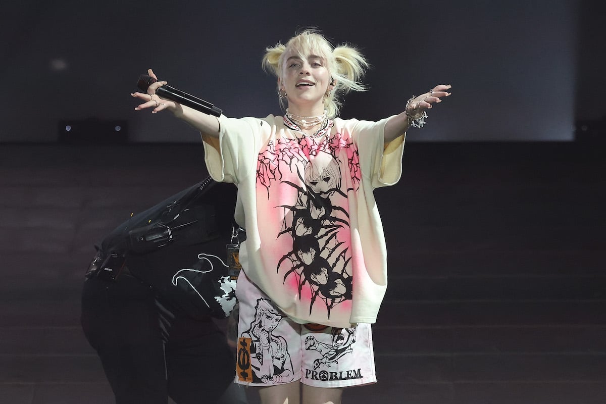 Billie Eilish stretches her arms out to the audience during a performance.