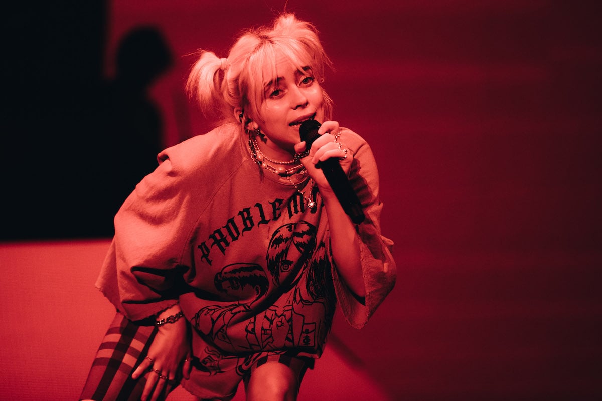 Billie Eilish performs on stage lit with red lighting.