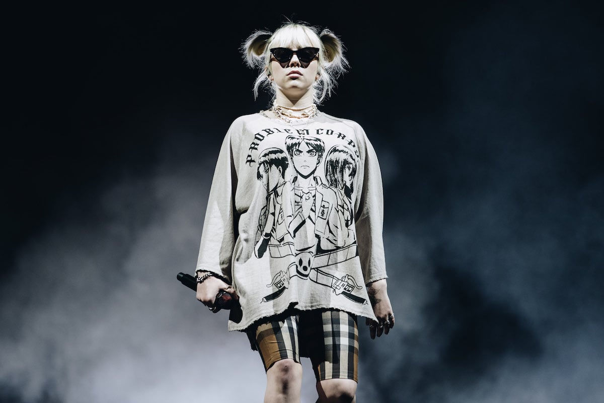 Billie Eilish performs on stage against a smoky black background.