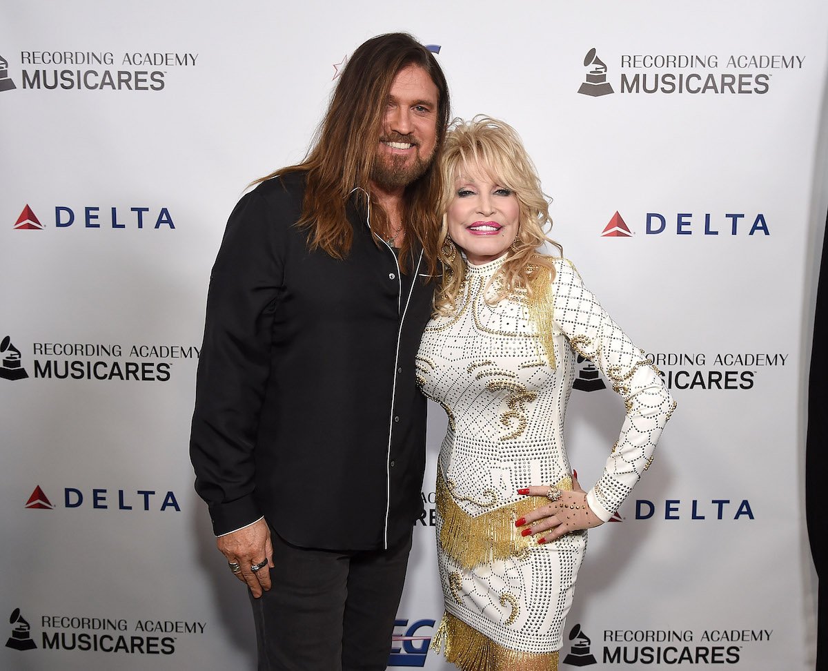 Billy Ray Cyrus and Dolly Parton pose together at an event.