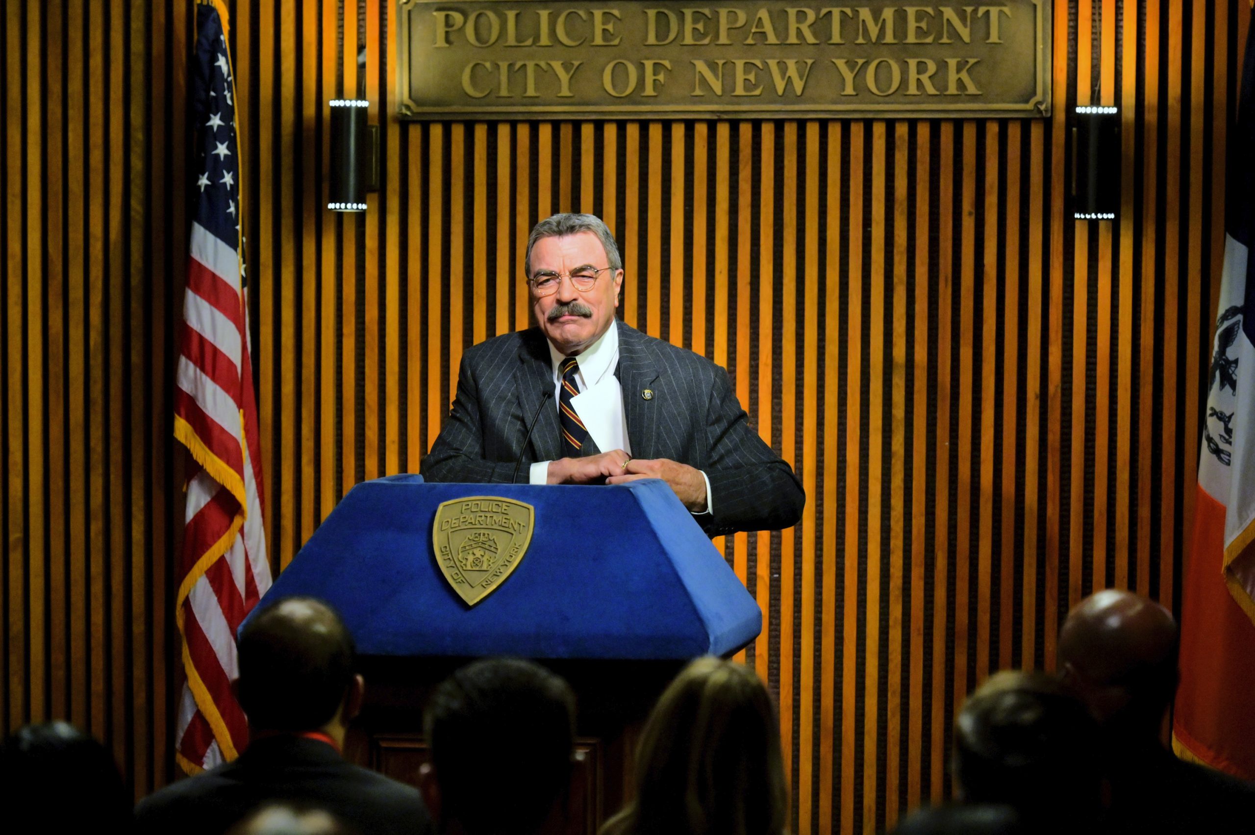 Tom Selleck as Frank Reagan stands at a podium for a press conference on 'Blue Bloods'
