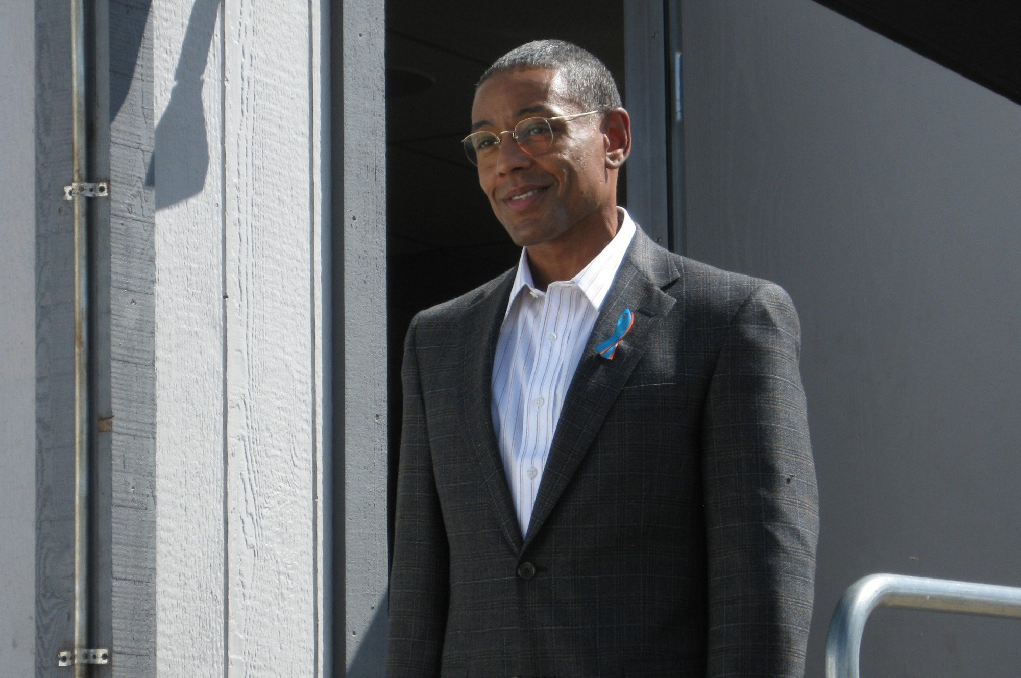 Giancarlo Esposito as Gus Fring in AMC's 'Breaking Bad.' He's wearing a suit and glasses and smiling.