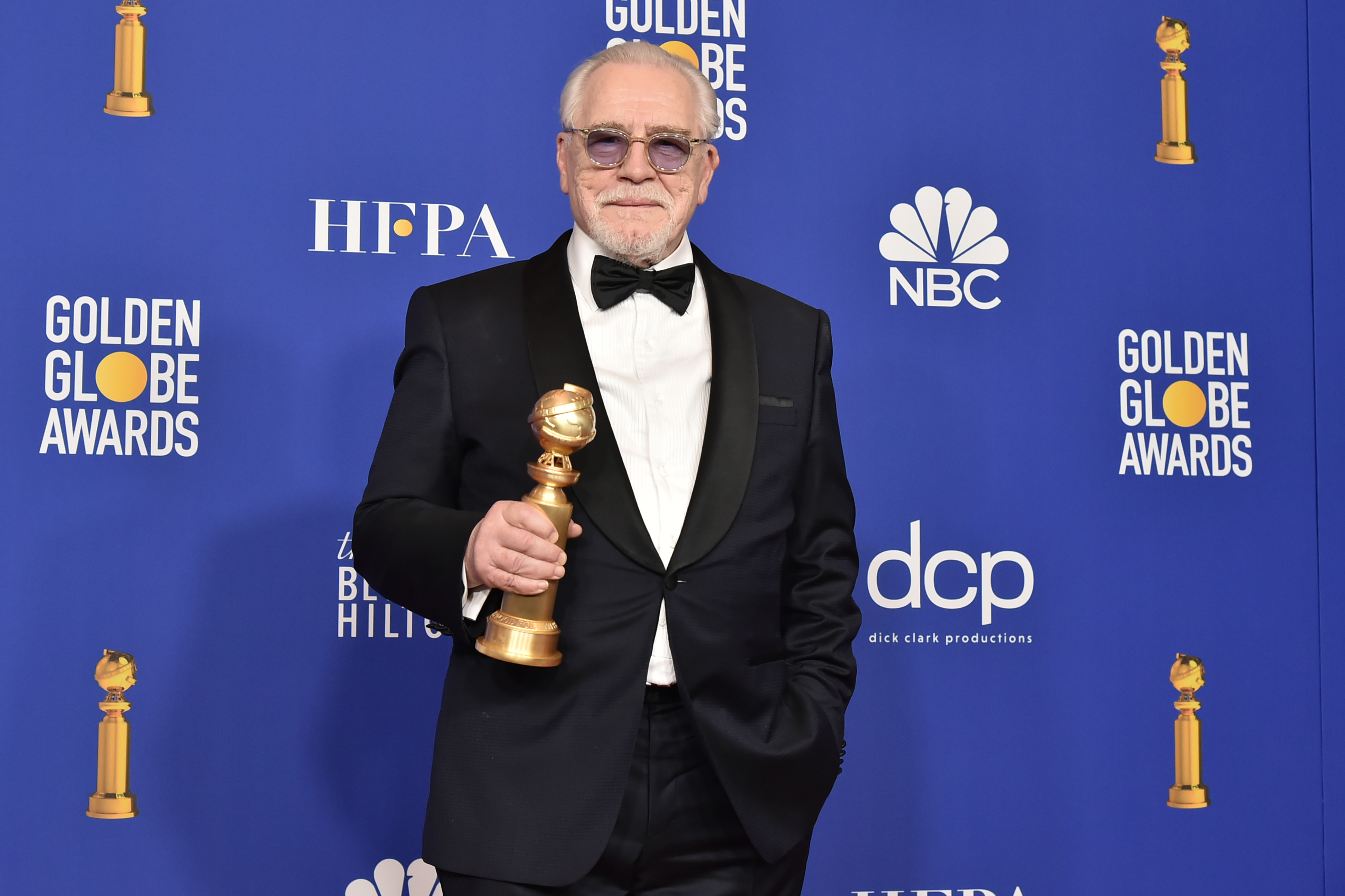 Succession actor Brian Cox in a tuxedo and sunglasses with an award.