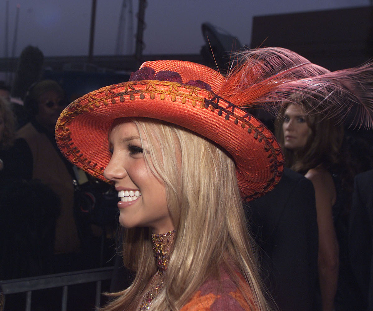 Britney Spears wearing an orange hat with a feather