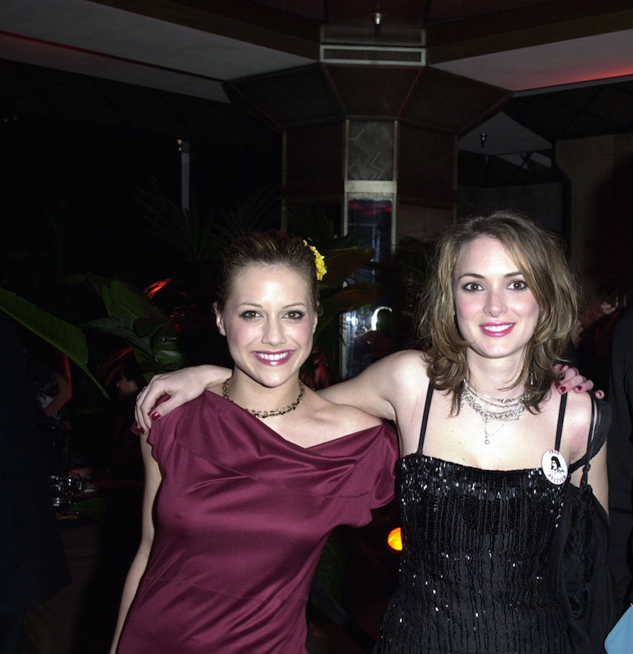 Brittany Murphy and Winona Ryder smile with their arms over each other's shoulders