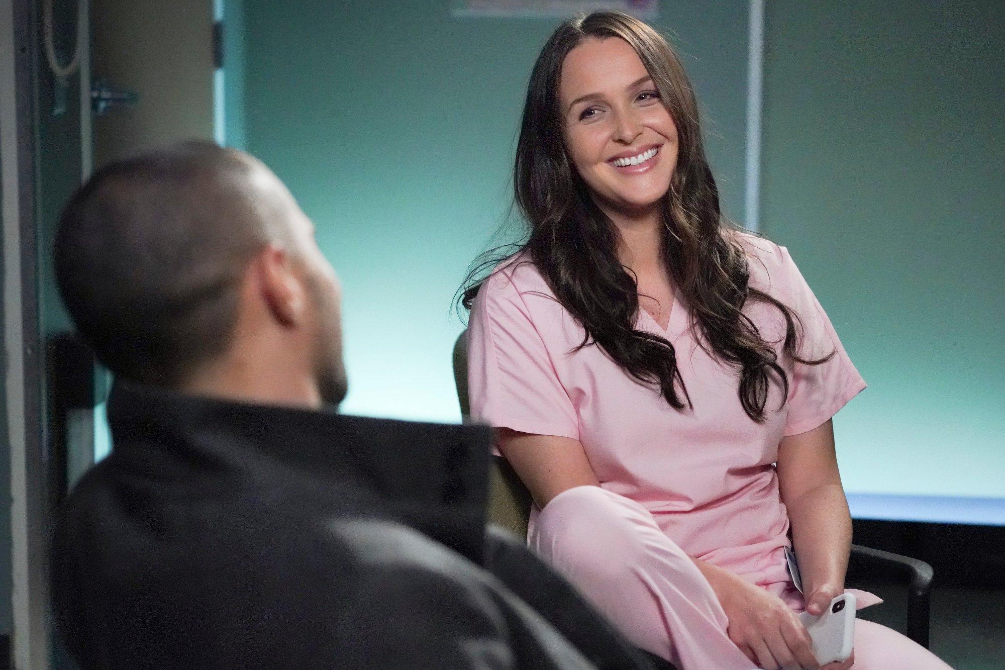 Camilla Luddington as Jo in ABC's 'Grey's Anatomy.' She's sitting in pink scrubs and laughing.