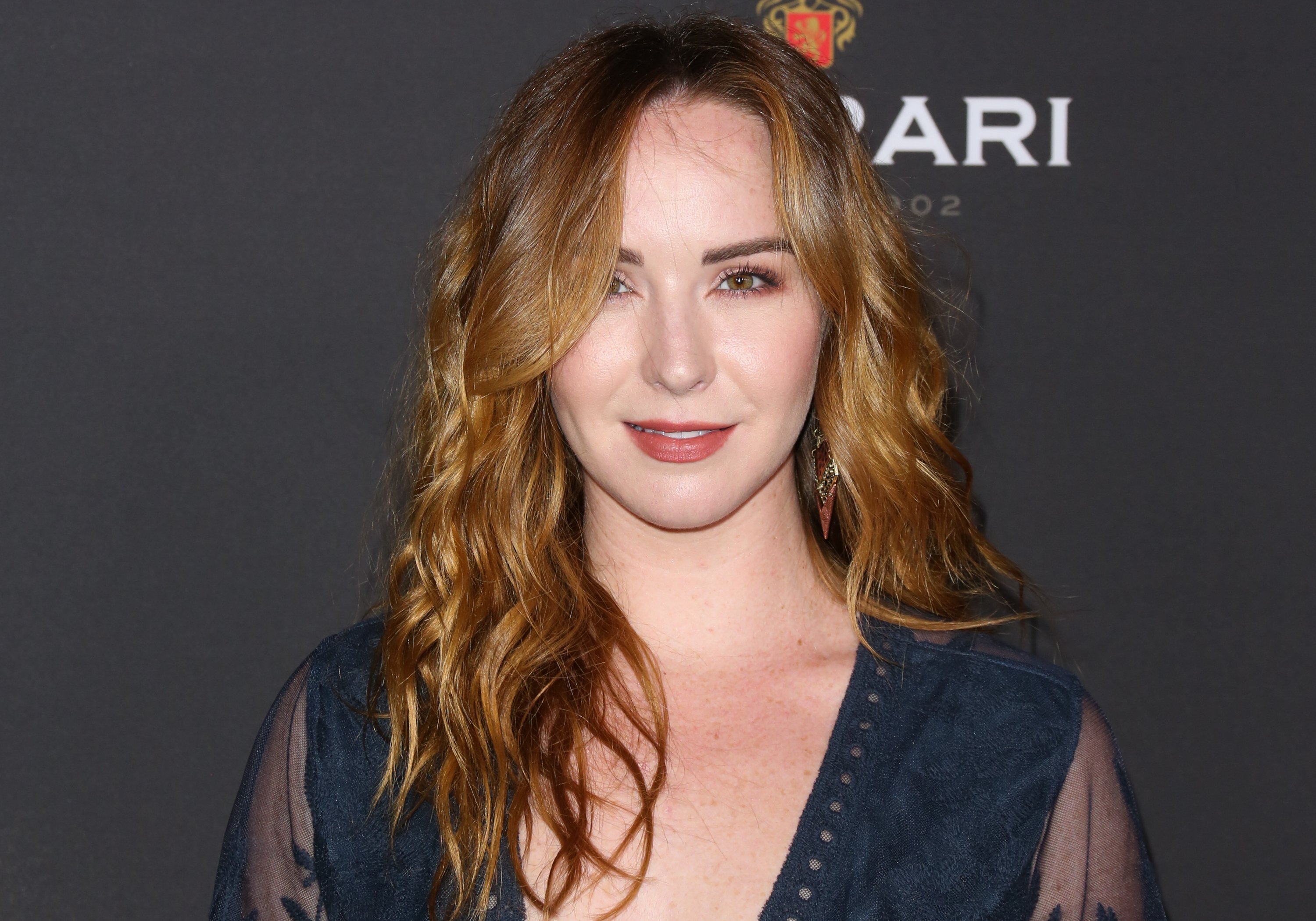 'The Young and the Restless' actor Camryn Grimes wearing a blue dress and smiling for photographers on the red carpet.