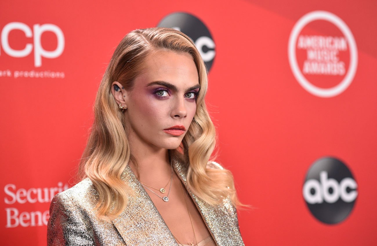 Cara Delevingne looking into camera in front of red background