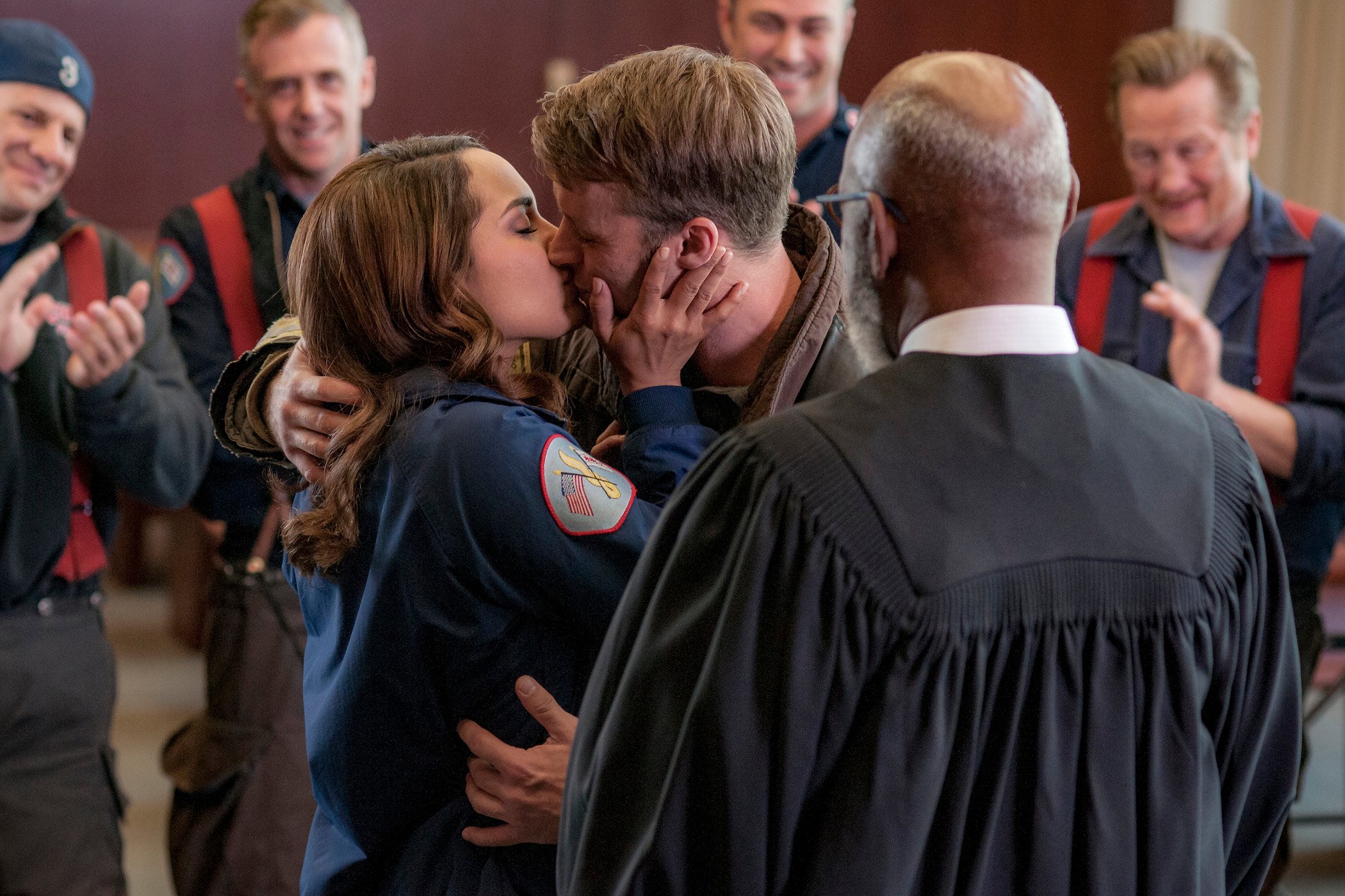Monica Raymund as Gabriela Dawson and Jesse Spencer as Matthew Casey kissing while surrounded by other firefighters. Raymund teased a possible return in 'Chicago Fire' Season 10