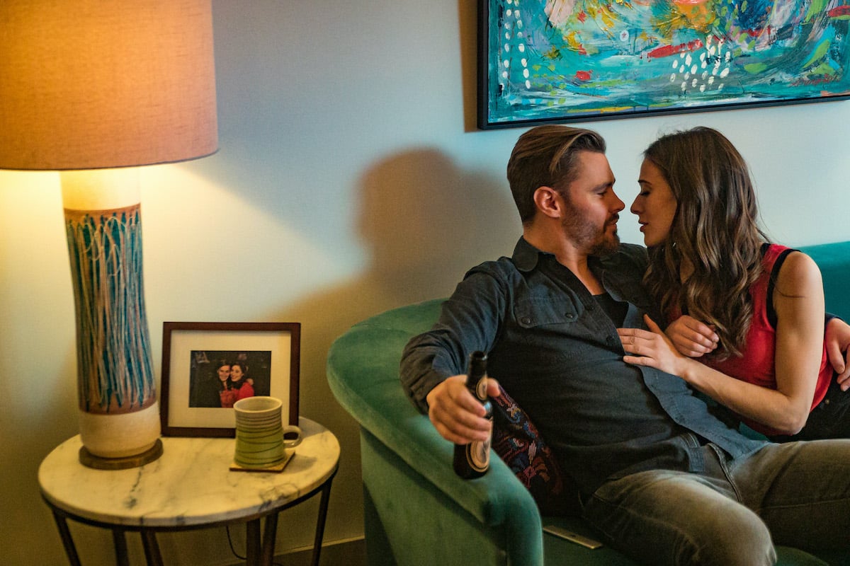 Kim and Adam on a couch, cuddling, smiling in a scene from Chicago P.D.