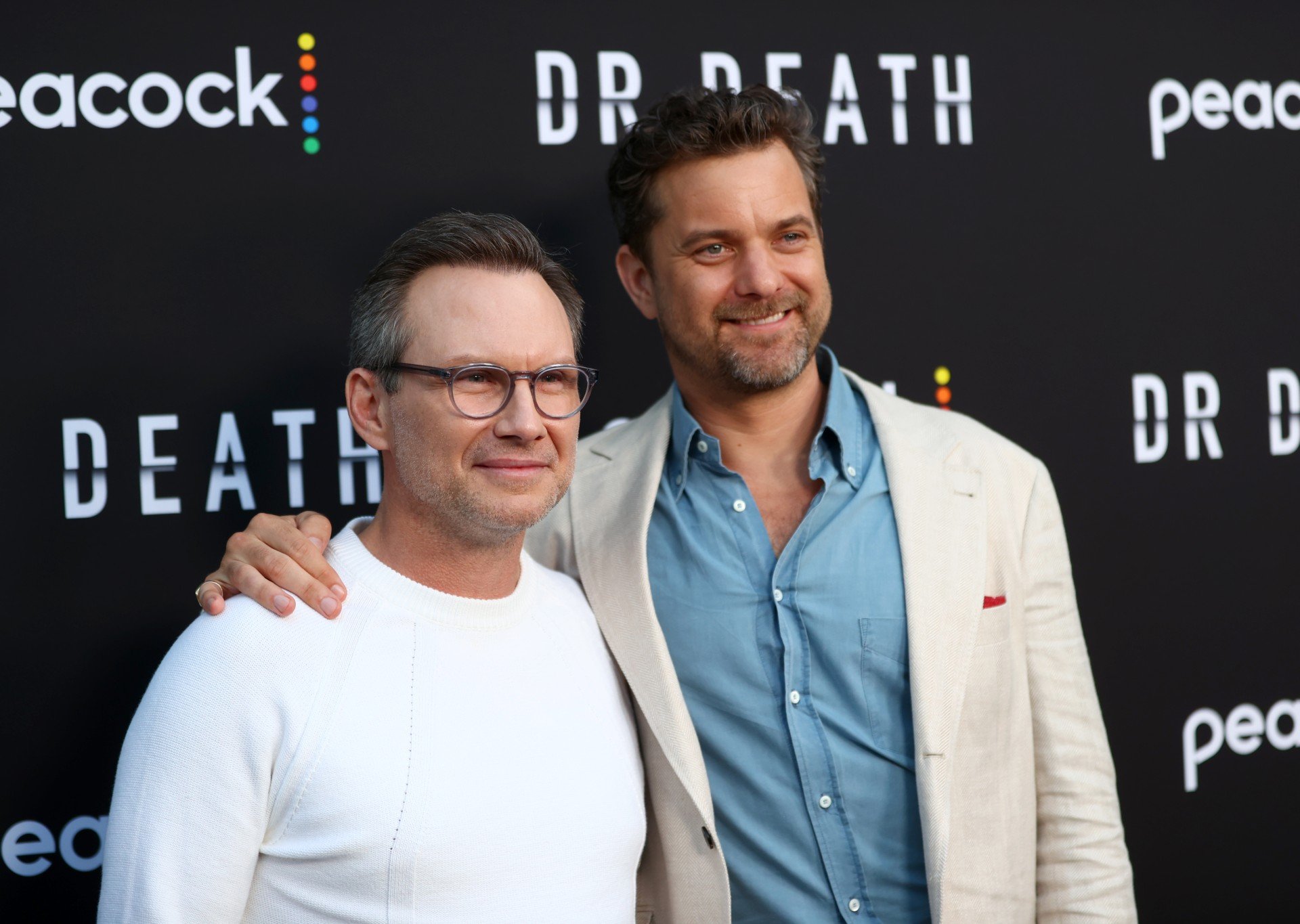 Christian Slater and Joshua Jackson pose on the red carpet at the Dr. Death premiere. 