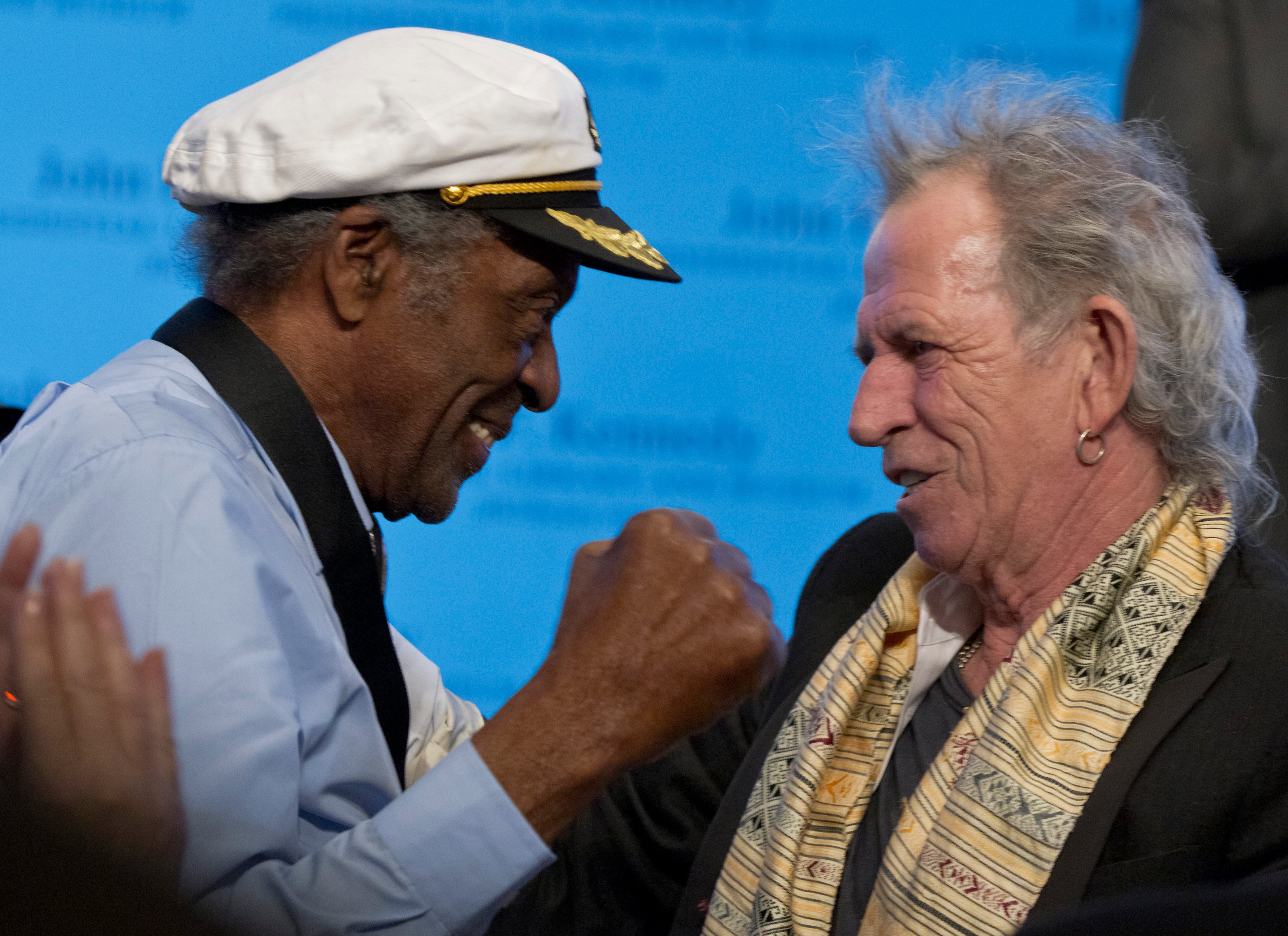 Chuck Berry and Keith Richards face each other onstage, smiling.