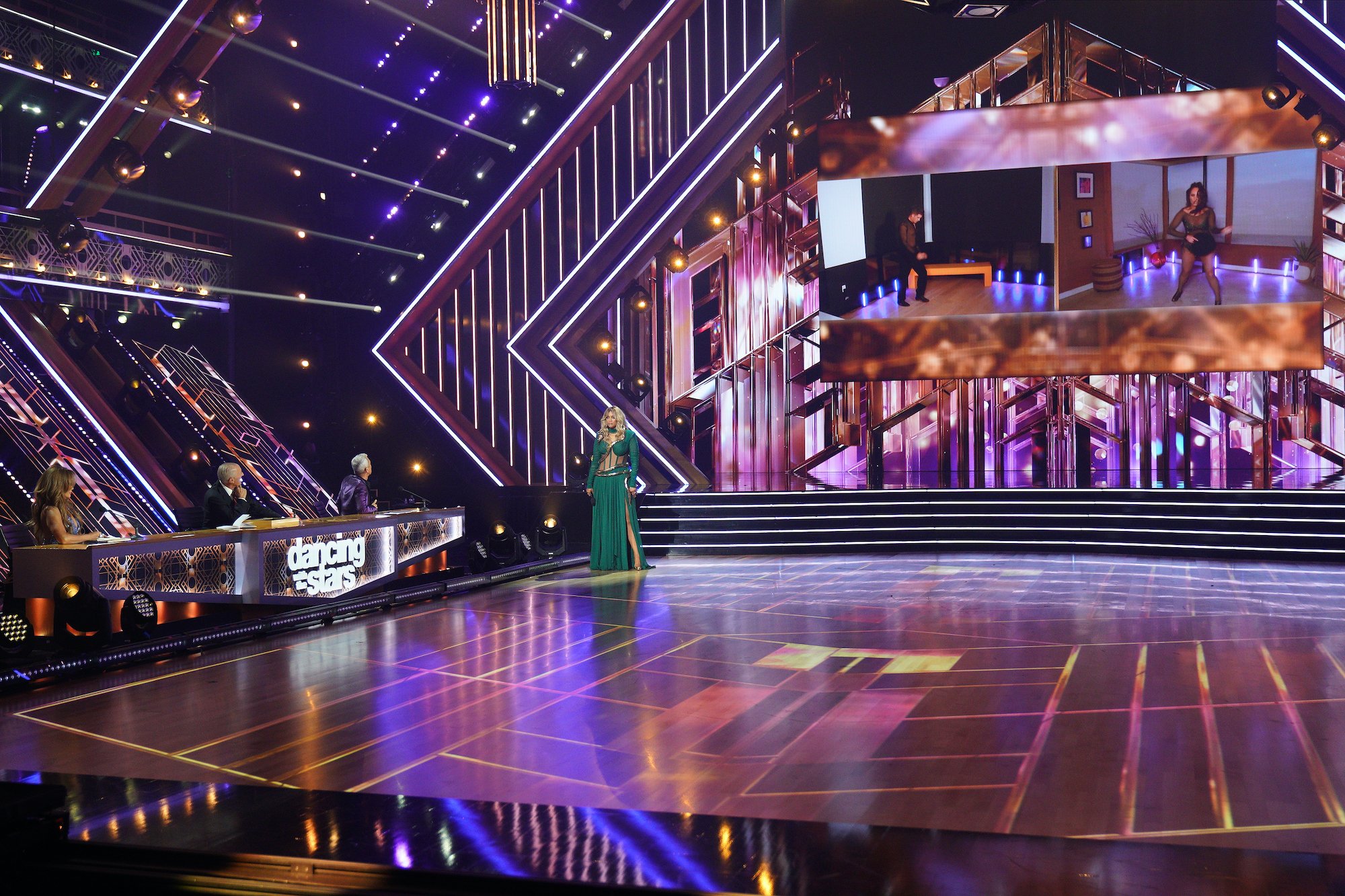 Carrie Ann Inaba, Len Goodman, and Bruno Tonioli sit at the judges table; Tyra Banks stands in the 'Dancing With the Stars' ballroom as Cody Rigsby and Cheryl Burke are projected onto the screen for their remote performance