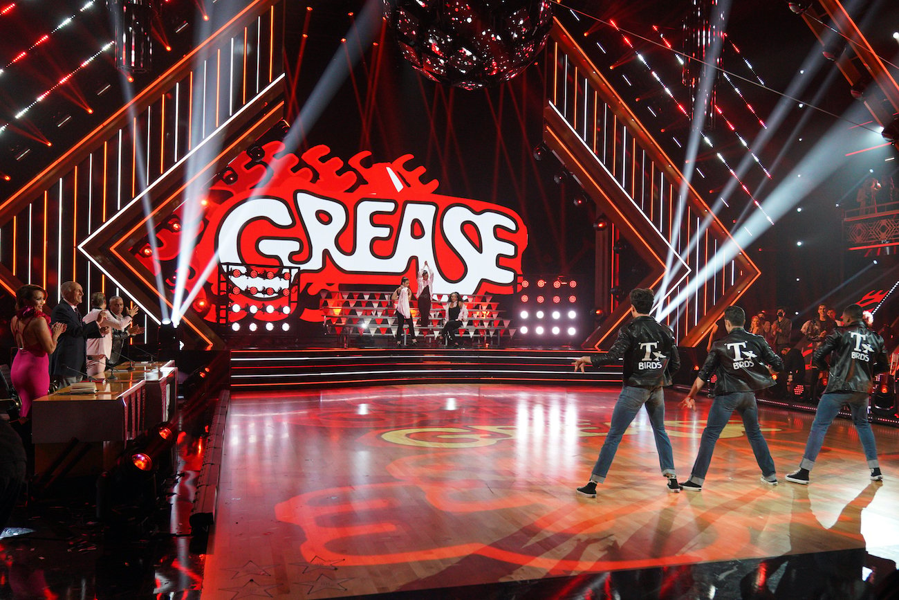 Judges Carrie Ann Inaba, Len Goodman, Derek Hough, and Bruno Tonioli stand clapping as 'Dancing with the Stars' dancers perform the opening number during 'Grease' Night Season 30