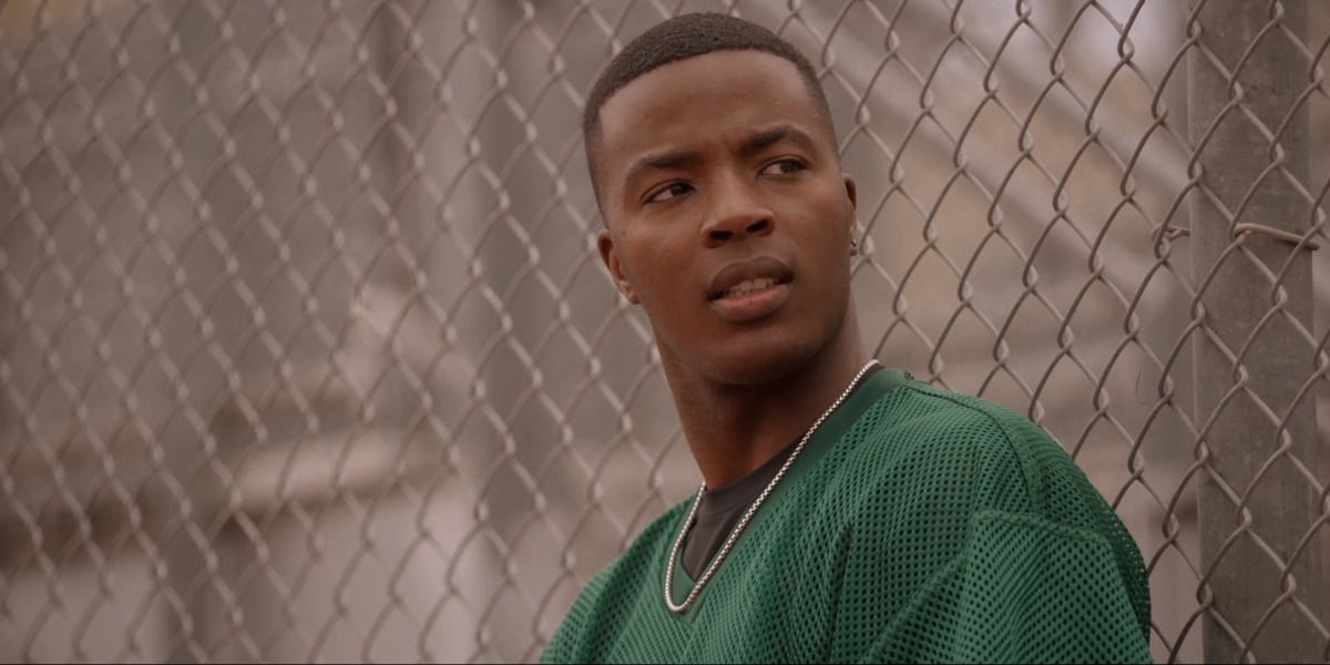 Daniel Ezra wearing a green football jersey in The CW series 'All American.'