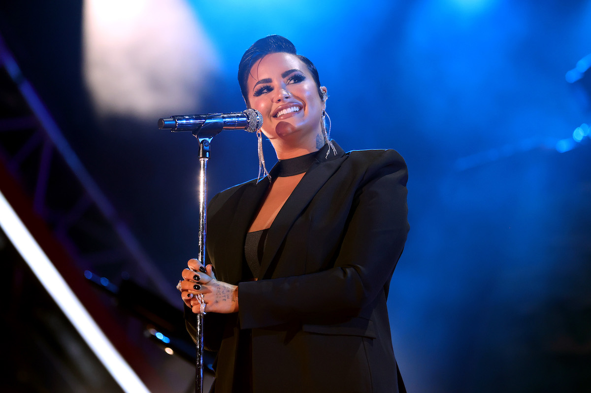 Demi Lovato smiles into a microphone on stage.