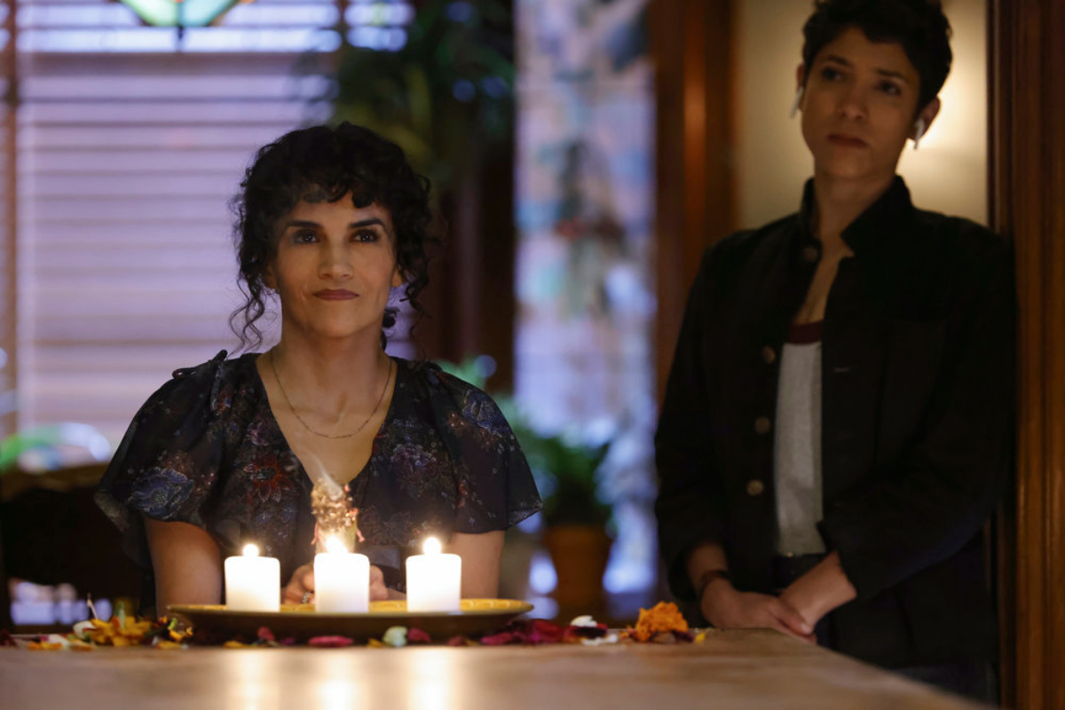 Katrina Arroyave as Mierce Xiu, Diany Rodriguez as Weecha Xiu in The Blacklist Season 9. The women are around a table with lit candles on it.