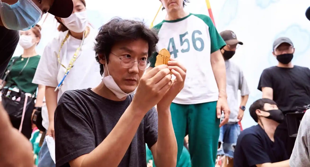 Director Hwang Dong-Hyuk for 'Squid Game' looking at Dalgona candy with 'Squid Game' cast. Hwang is creating 'Squid Game' Season 2
