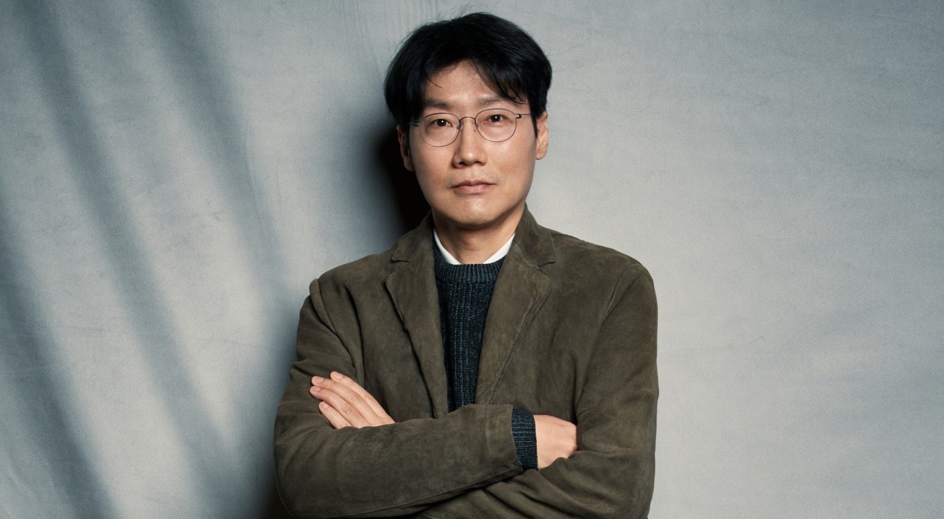 Director Hwang Dong-hyuk of 'Squid Game' Netflix K-drama wearing tweed jacket with arms crossed.