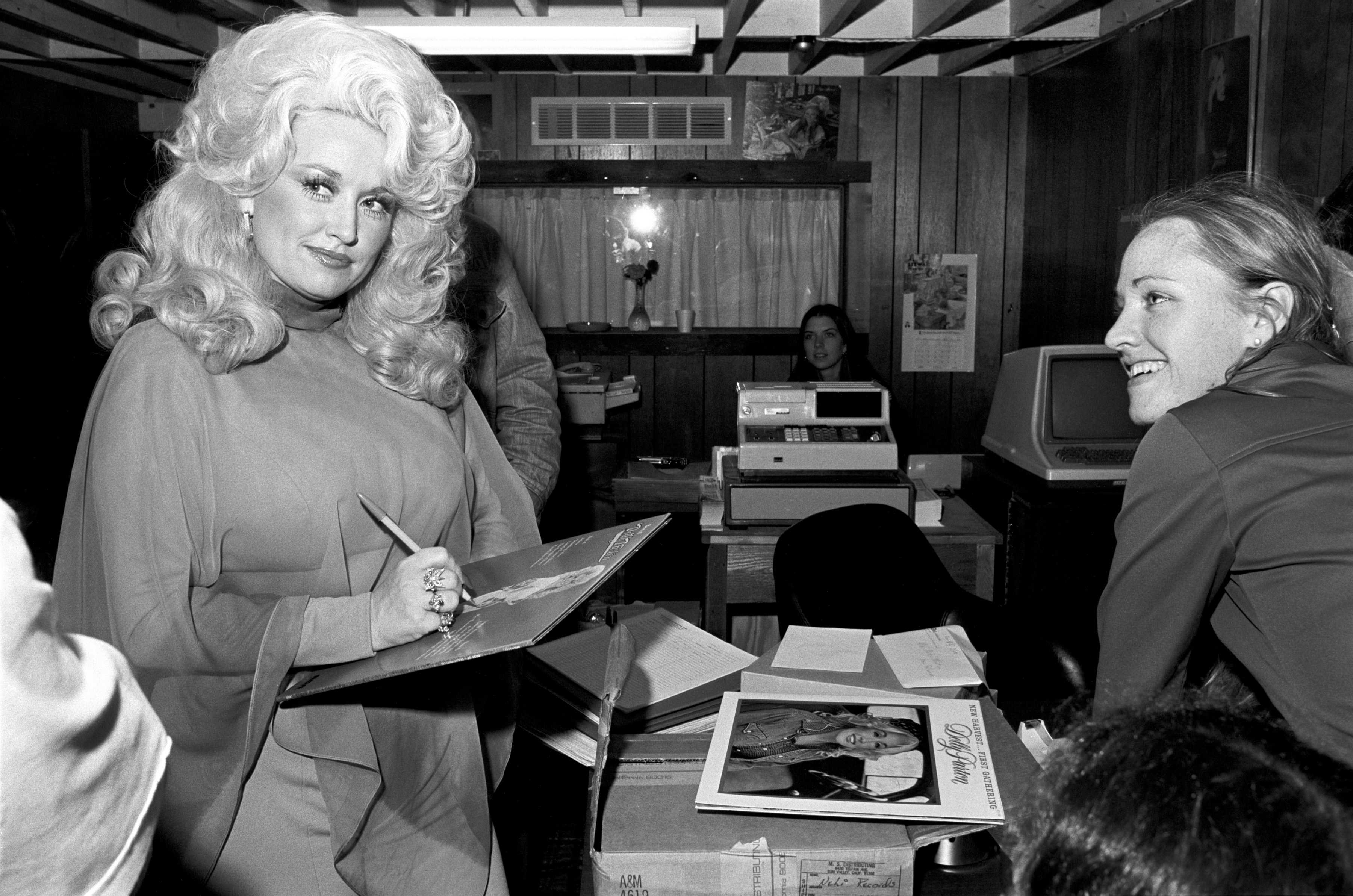 Dolly Parton signs a fan's record at Peaches Records. 