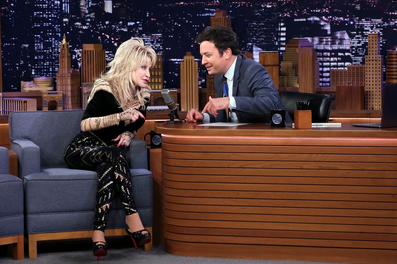 Dolly Parton in a black outfit and Jimmy Fallon in a suit talk to one another on 'The Tonight Show with Jimmy Fallon.