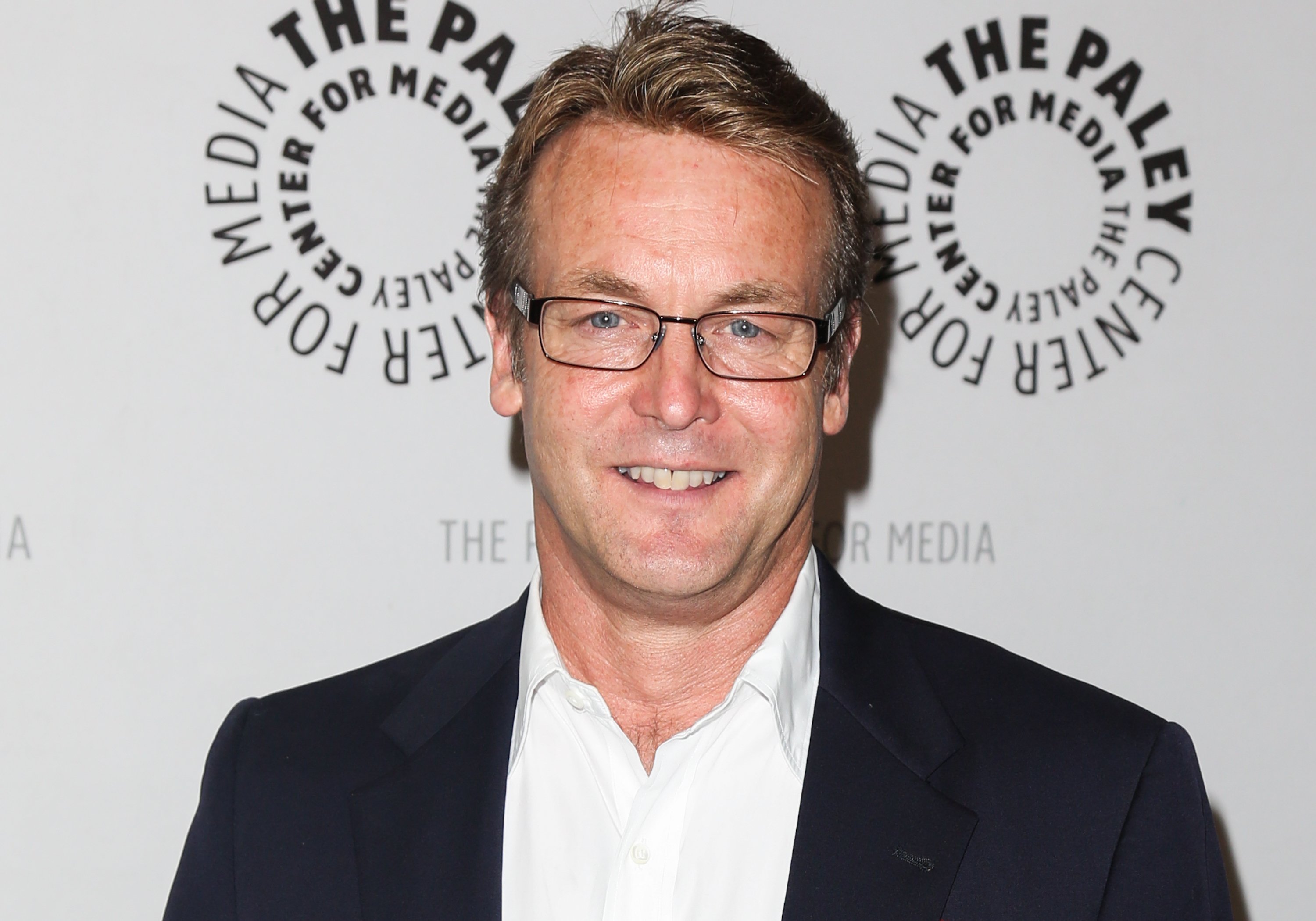 'The Young and the Restless' actor Doug Davidson in a white shirt, black jacket, and glasses, smiling for the camera.
