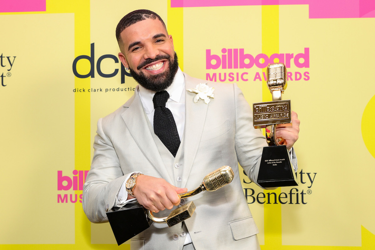 Drake holds up two awards at an event.