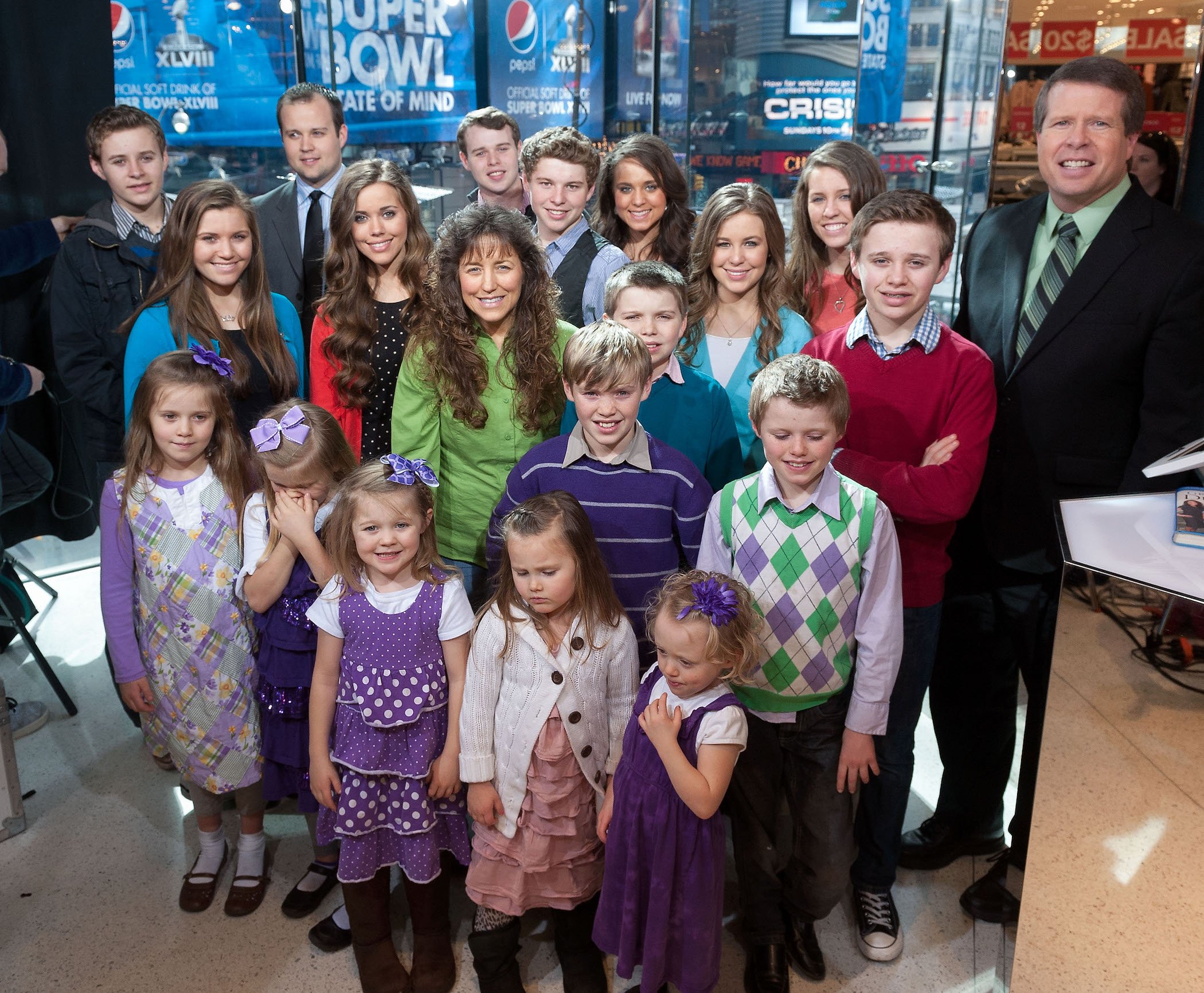 The Duggar family, including Josh Duggar, all standing together smiling while visiting 'Extra.' The latest Duggar news typically surrounds Josh.