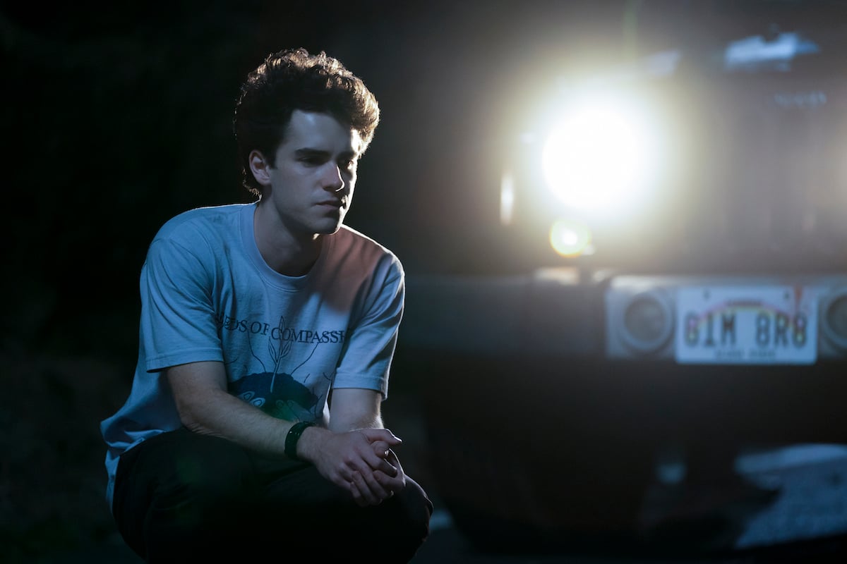 Dylan kneeling in front of car with Hawaii license plate in 'I Know What You Did Last Summer'