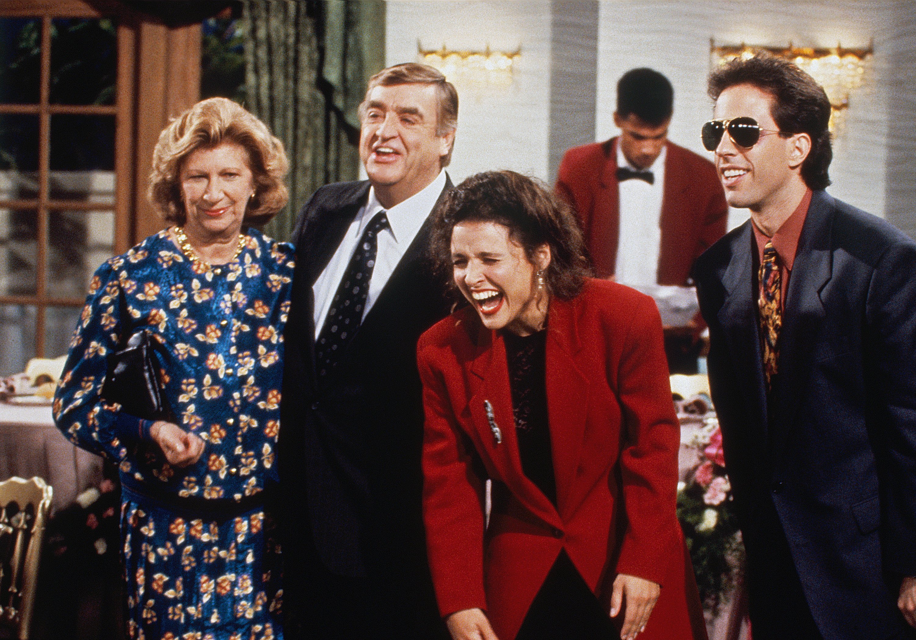 Elaine Benes in 'The Pen' for 'Seinfeld' bending over laughing in red blazer