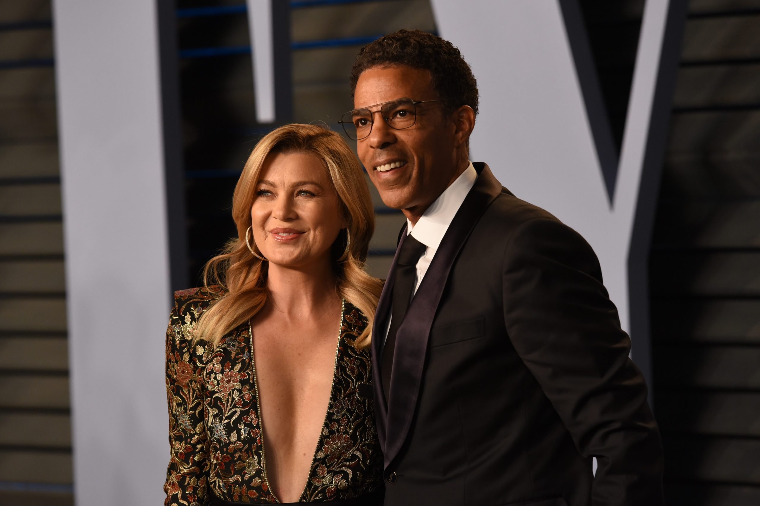 Ellen Pompeo wears a low cut dress and Chris Ivery wears a suit on the carpet of the 2018 Vanity Fair Oscar Party