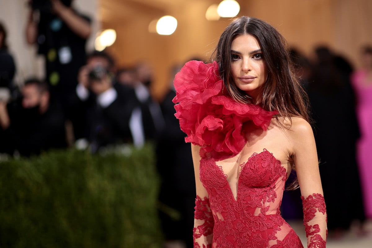 Emily Ratajkowski poses in an elaborate red gown at an event.