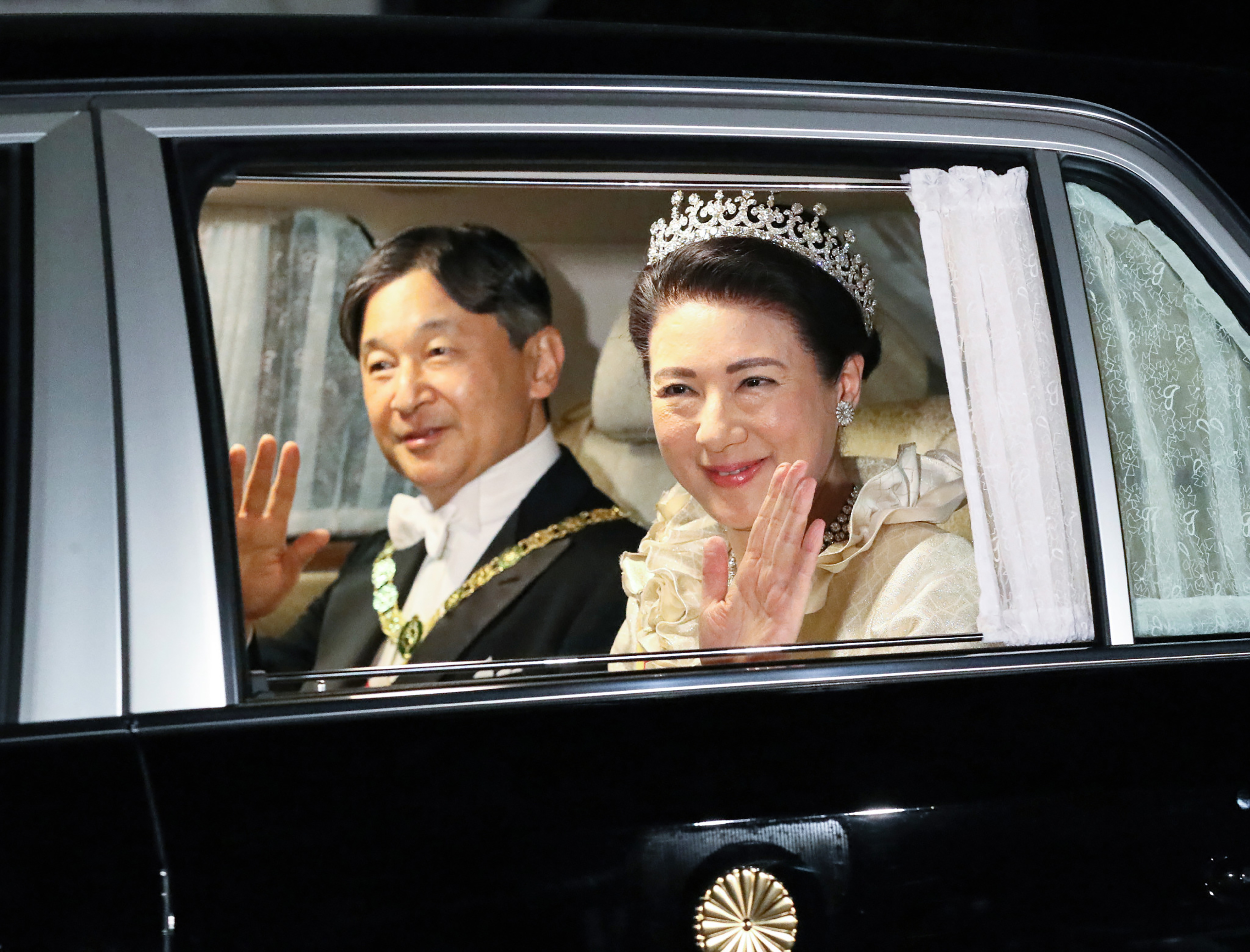 Emperor Naruhito and Empress Masako smile and wave as they depart Akasaka Palace for the court banquet at the Imperial Palace