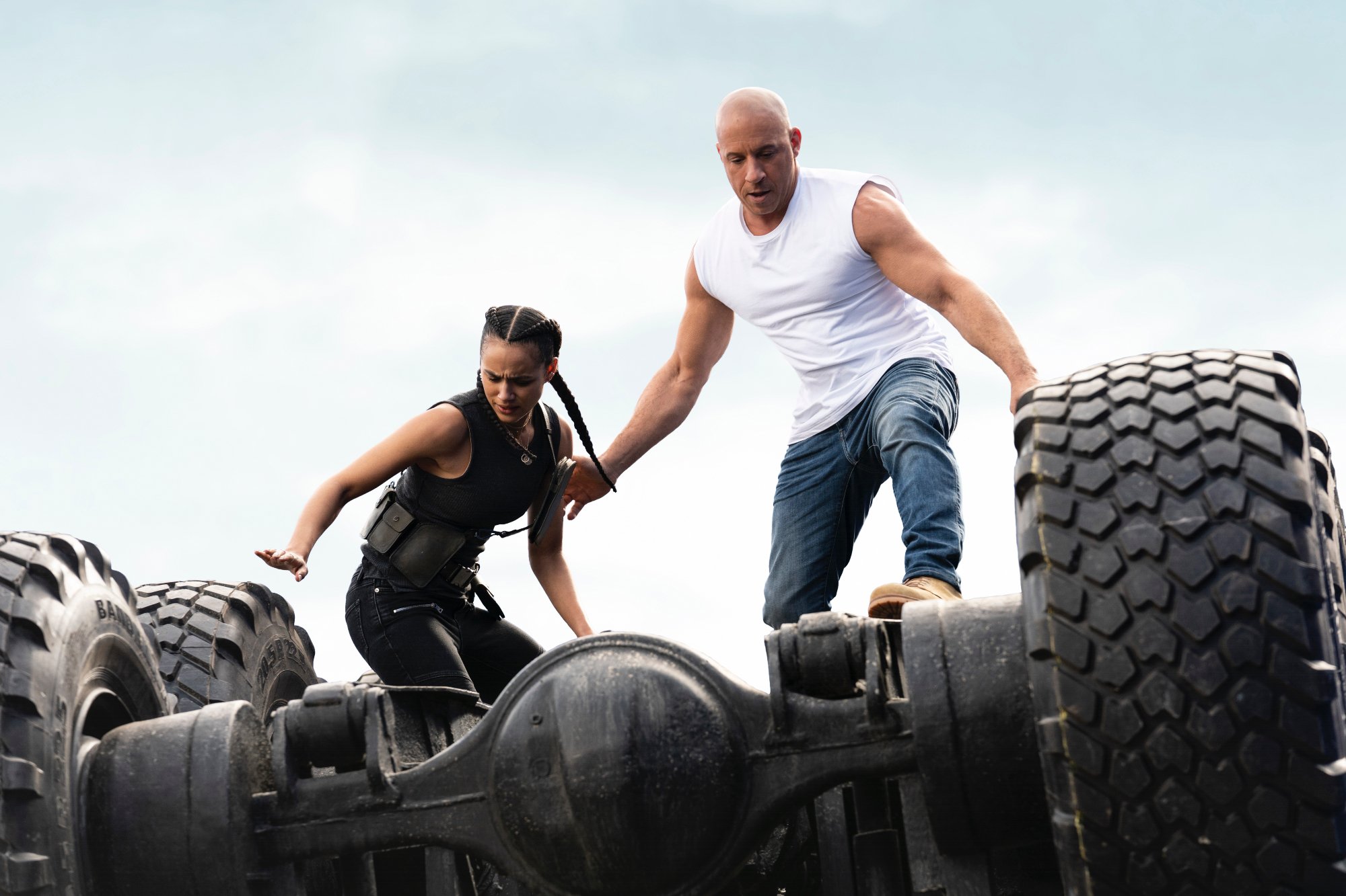 'Fast & Furious' actors Nathalie Emmanuel as Ramsey and Vin Diesel as Dom standing on the underside of a car in 'F9'