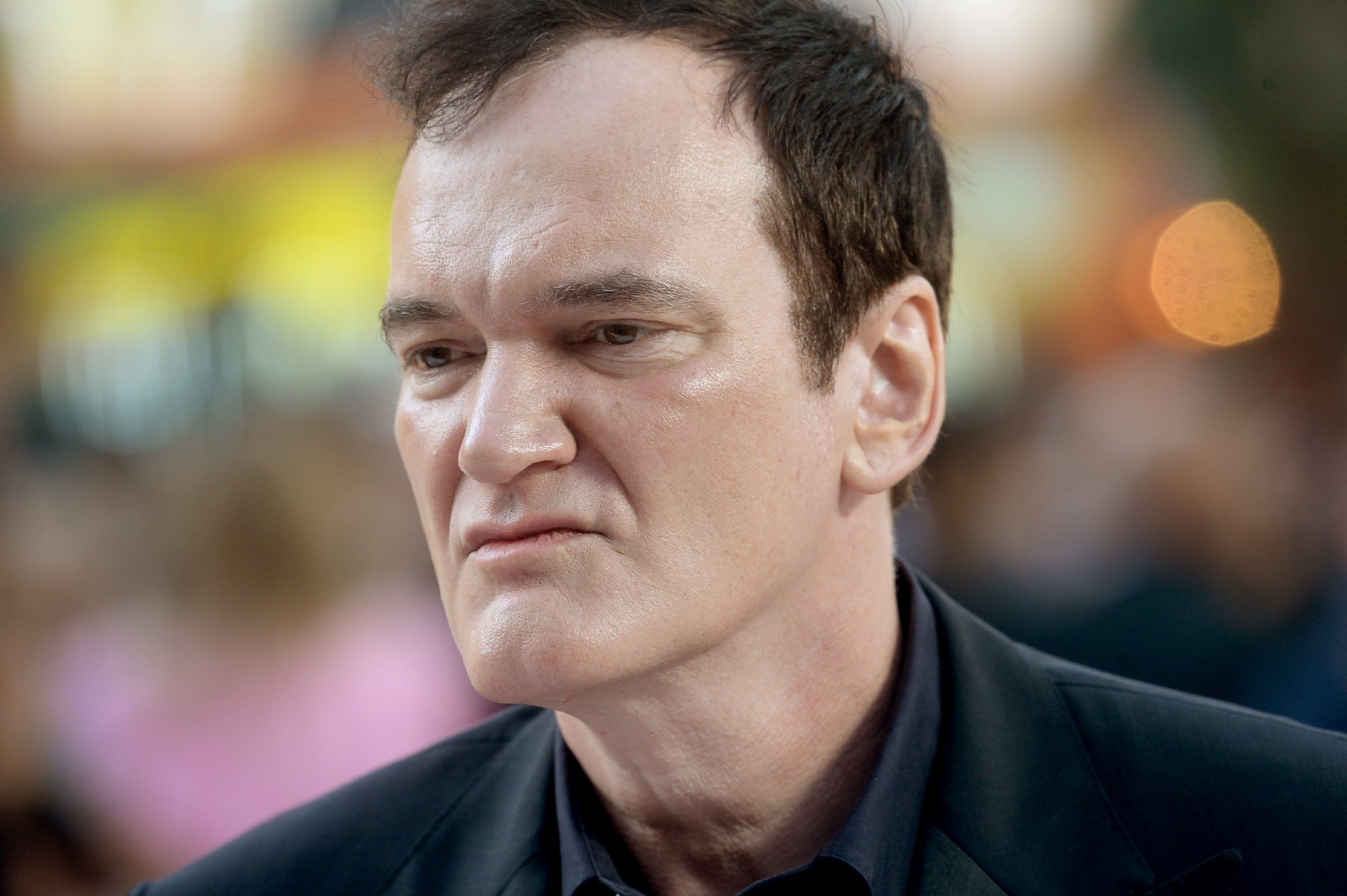 Filmmaker Quentin Tarantino at the 'Once Upon a Time in Hollywood' U.K. premiere wearing a black jacket and dark blue collared shirt