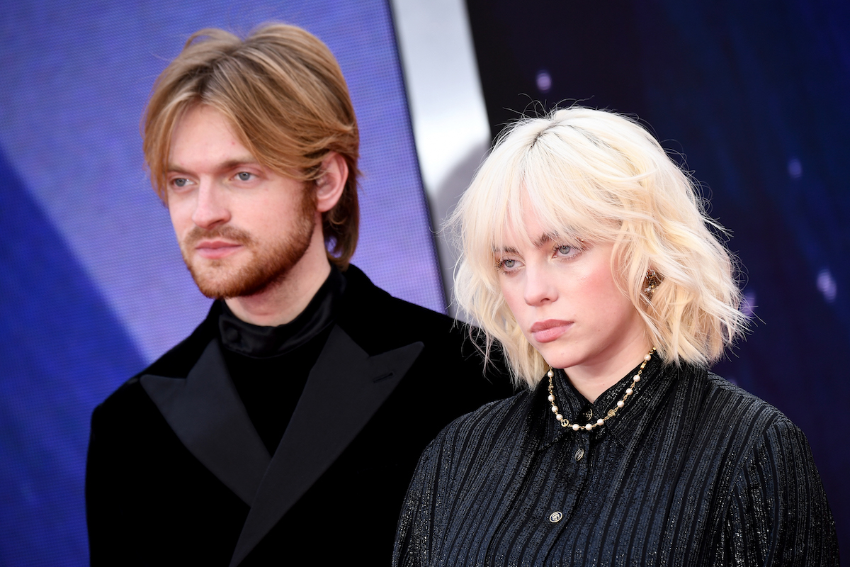 Finneas O'Connell and Billie Eilish pose together in matching black outfits at an event.