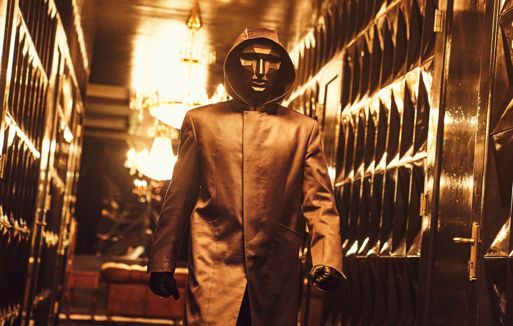 Front Man character in 'Squid Game' K-drama wearing coat and mask walking down hallway