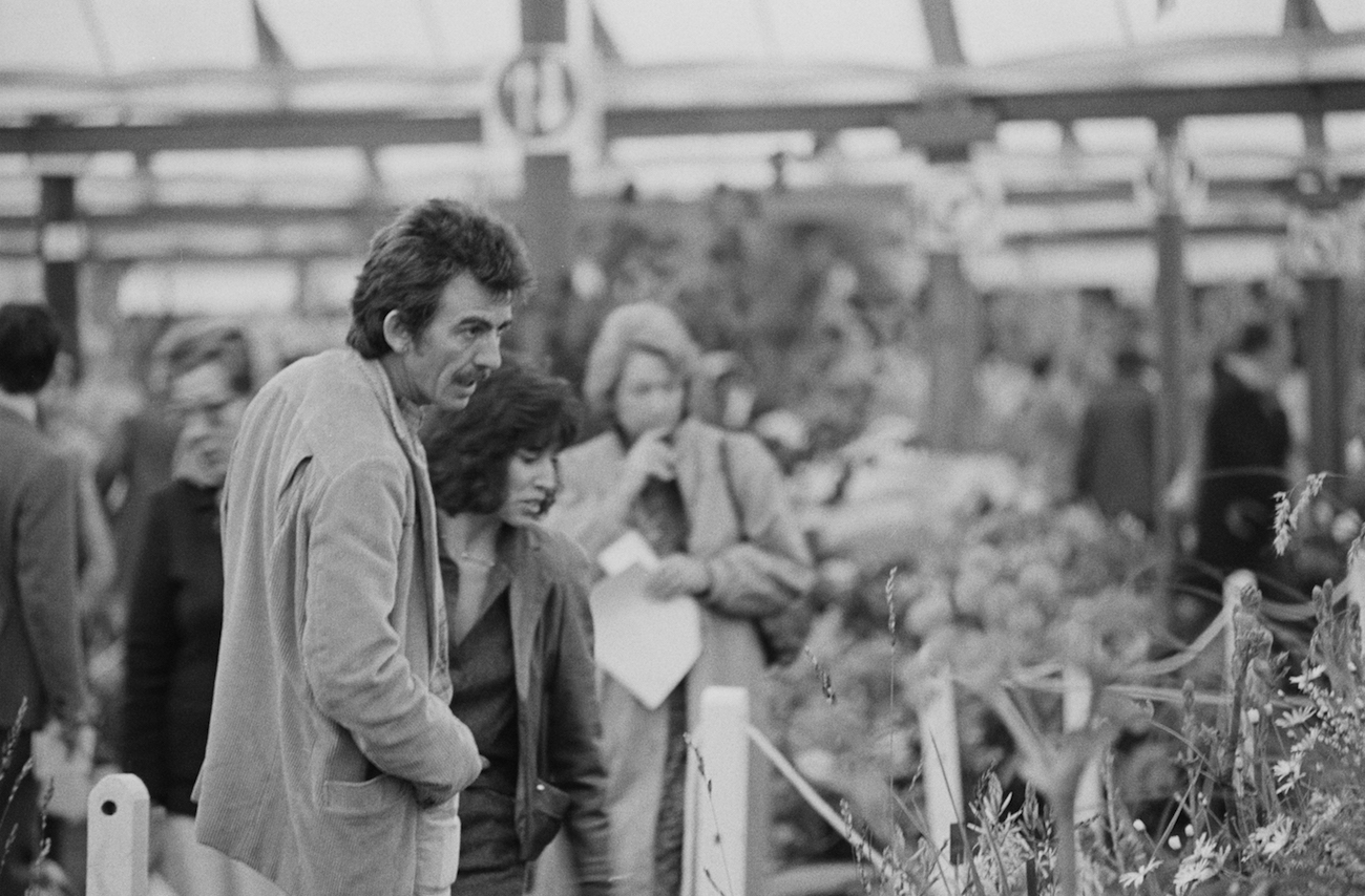 George Harrison wearing white and his wife Olivia wearing black at the Chelsea Flower Show in 1984. 